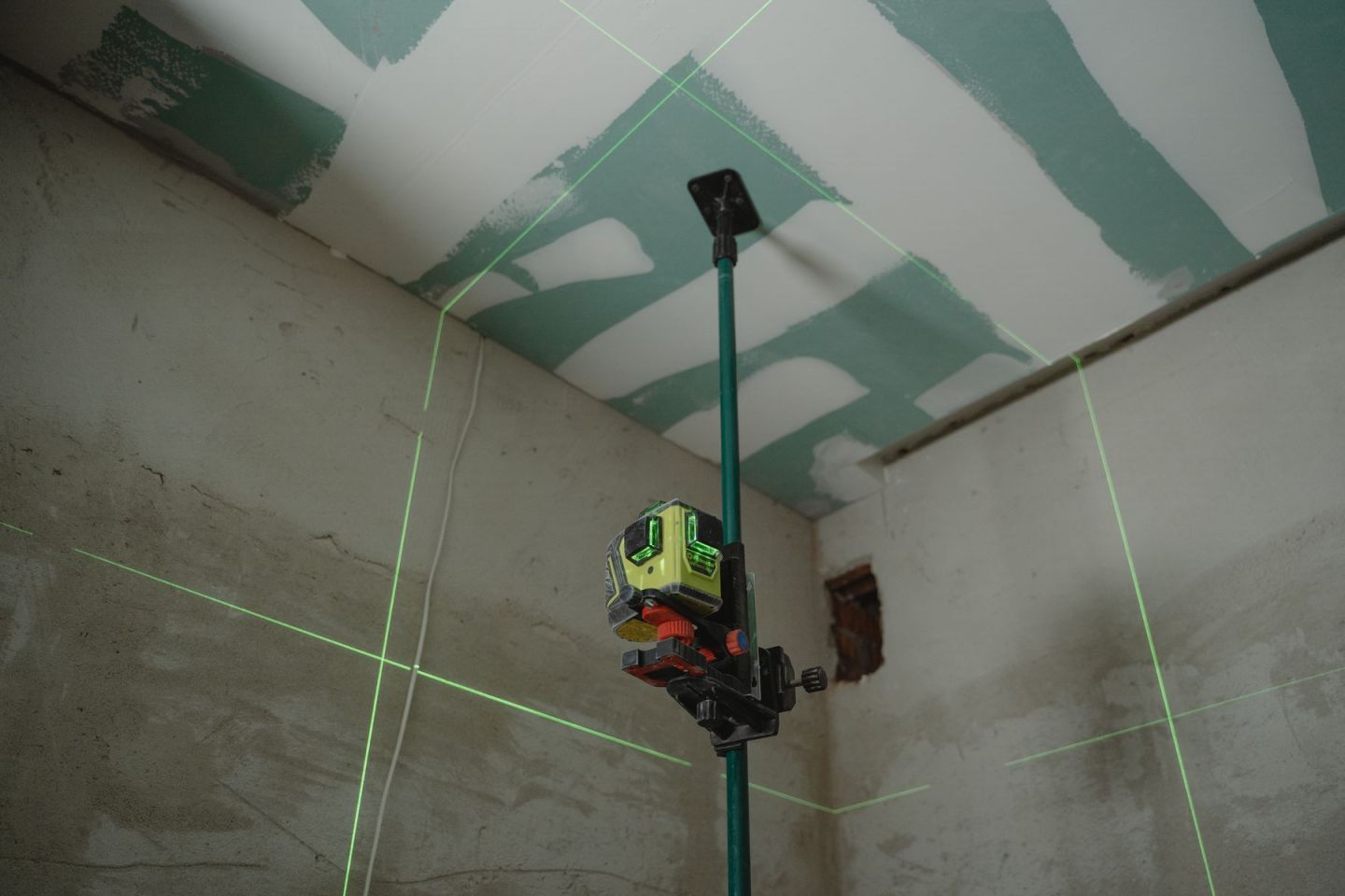 Kreuzlinienlaser projiziert die Höhenlinie für eine abgehängte Decke in einen Rohbauraum